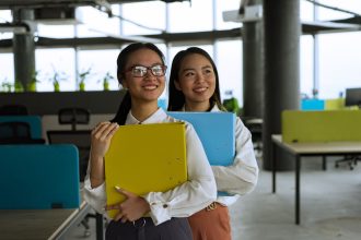 Duas profissionais sorrindo em um escritório moderno.