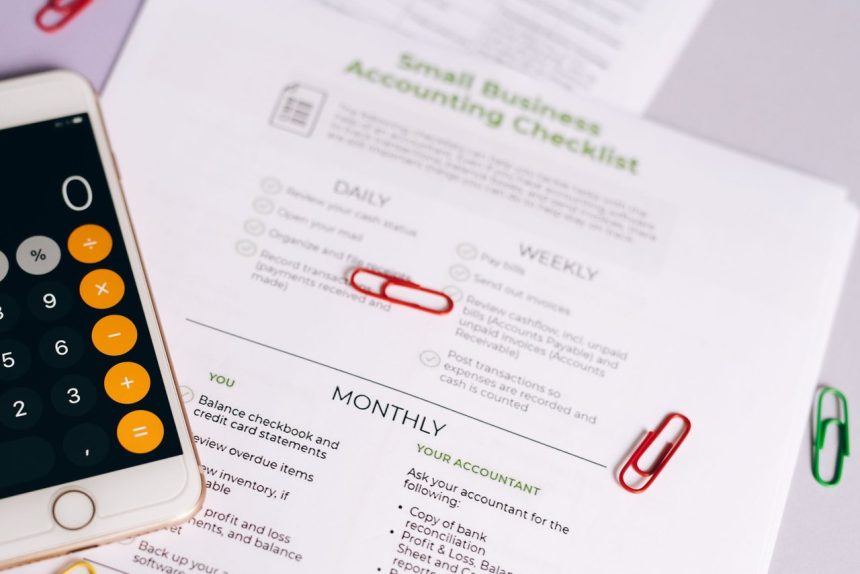 Checklist e calculadora sobre uma mesa, usados para organizar tarefas de contabilidade de um pequeno negócio.