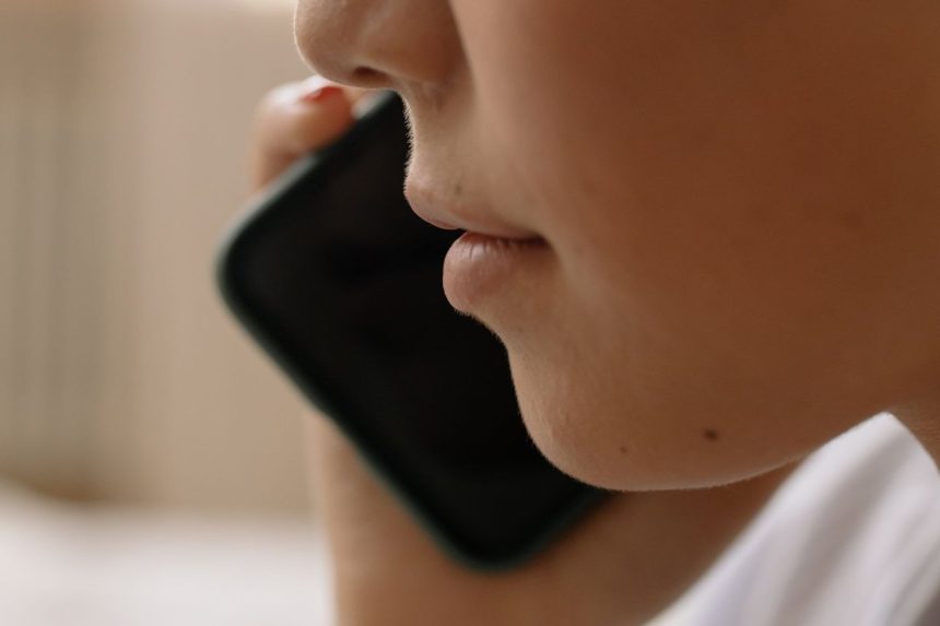 Pessoa falando ao telefone celular em um enquadramento aproximado.