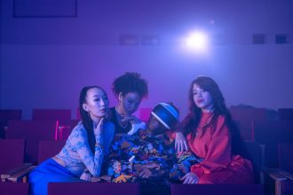 Pessoas sentadas em uma sala de cinema enquanto uma delas usa um headset de realidade virtual.
