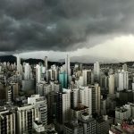 Nuvens carregadas sobre edifícios modernos do centro de uma cidade brasileira.