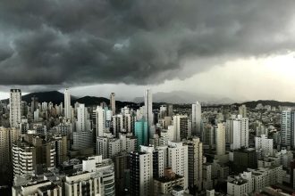 Nuvens carregadas sobre edifícios modernos do centro de uma cidade brasileira.