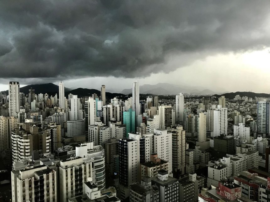 Nuvens carregadas sobre edifícios modernos do centro de uma cidade brasileira.