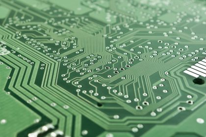 Close de uma placa de circuito impresso com trilhas, componentes eletrônicos e microprocessador.