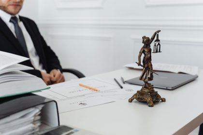 Mesa de trabalho jurídico com documentos, laptop e uma estátua da Justiça.